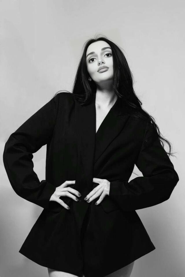 крупный план стильной женщины в жакете, которая уверенно смотрит в камеру